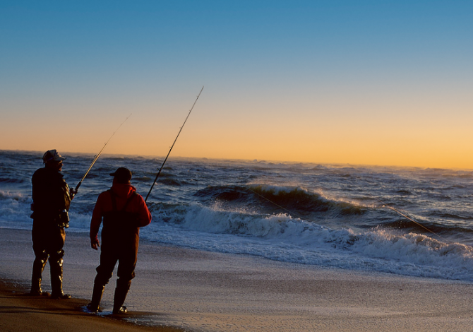 two fisherman shore fishing at dusk.